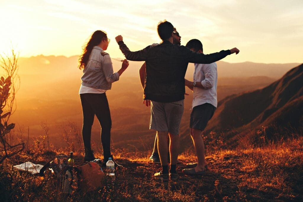 A group of well adjusted teens stands outside at sunset laughing together