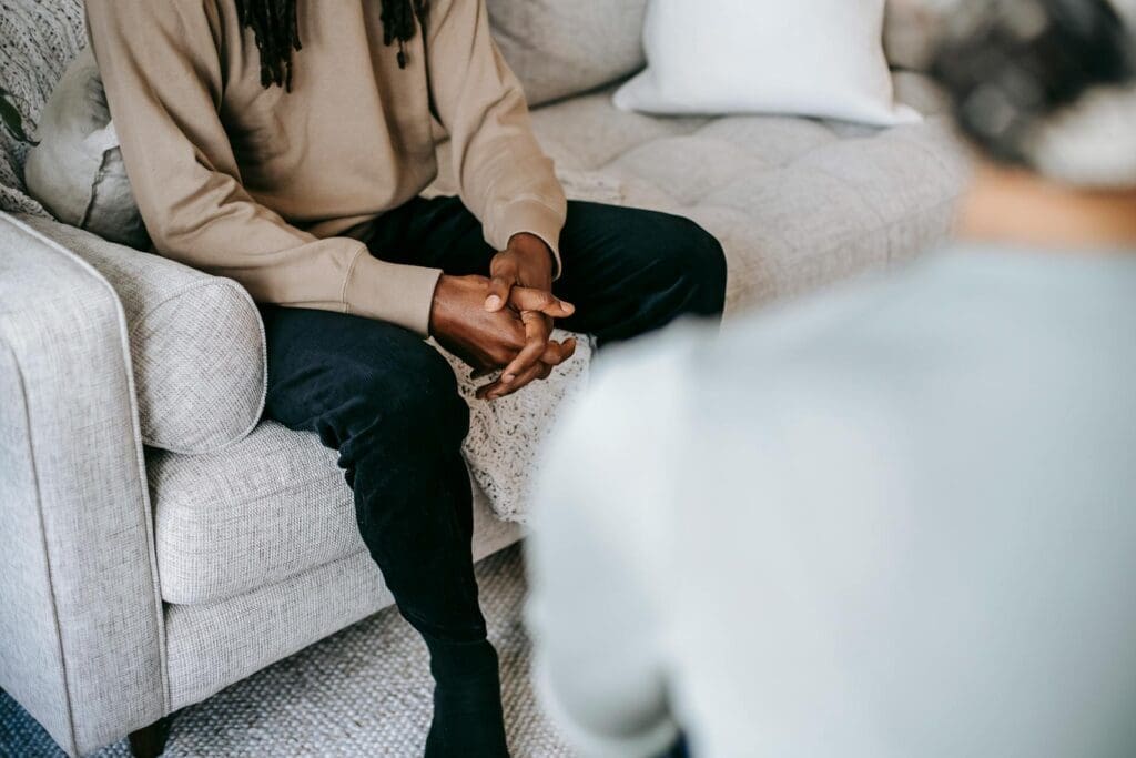 Cropped teenager sitting on a couch during a teen therapy session with hands folded