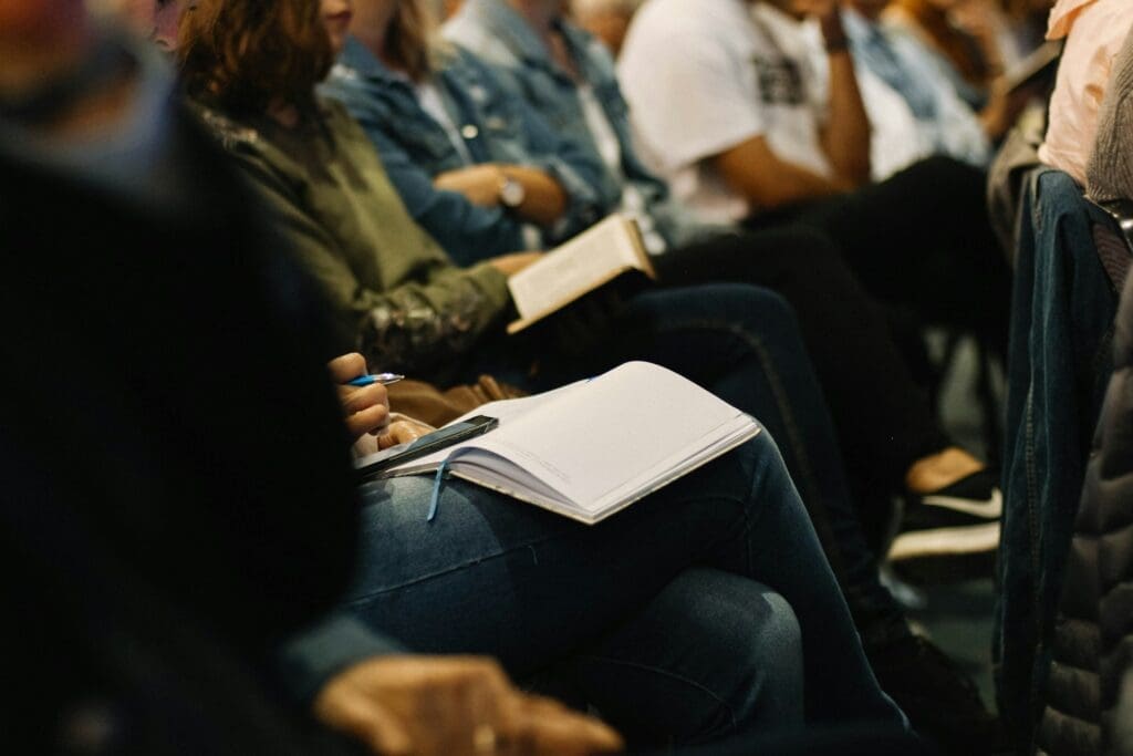 People sit with open notebooks and pens in their lap representing how group therapy for teens can tech them valuable skills