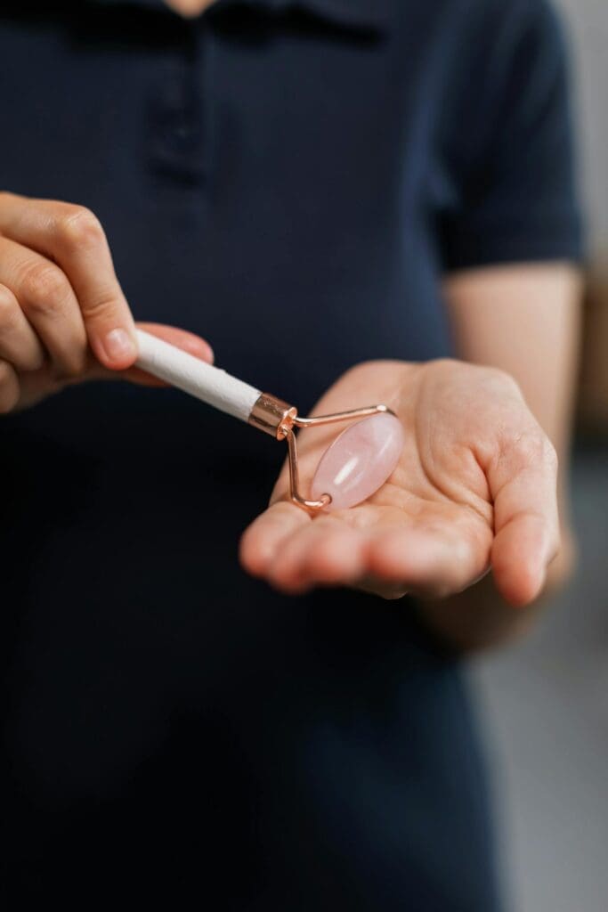 person holding a rose quartz face roller, an object that can be used as a sensory grounding object when treating anxiety