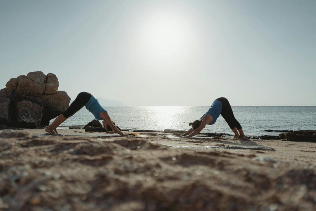 two people moving their bodies by doing yoga on the beach as an anxiety coping technique