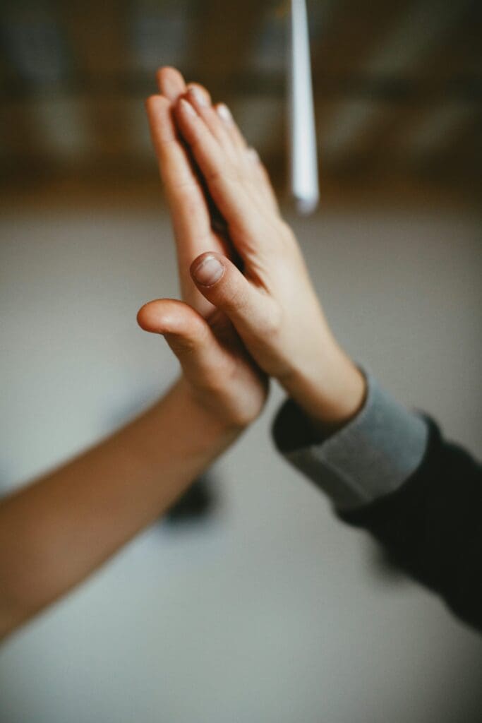 two people holding their hands up together palm against palm