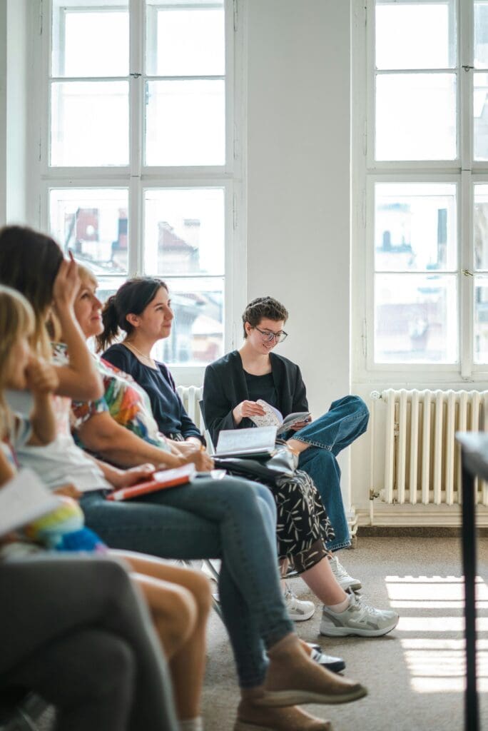 group of adults sitting together, listening and sharing information, notebooks on their laps, relaxed, comfortable